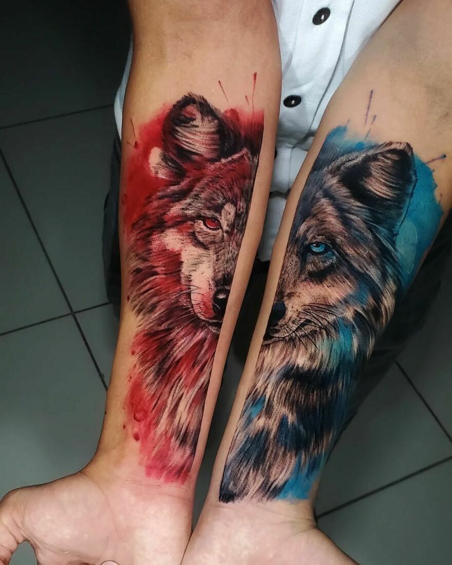 Two forearms with watercolor tattoos of wolf faces in red and blue.
Two forearms with watercolor tattoos of wolf faces in red and blue.