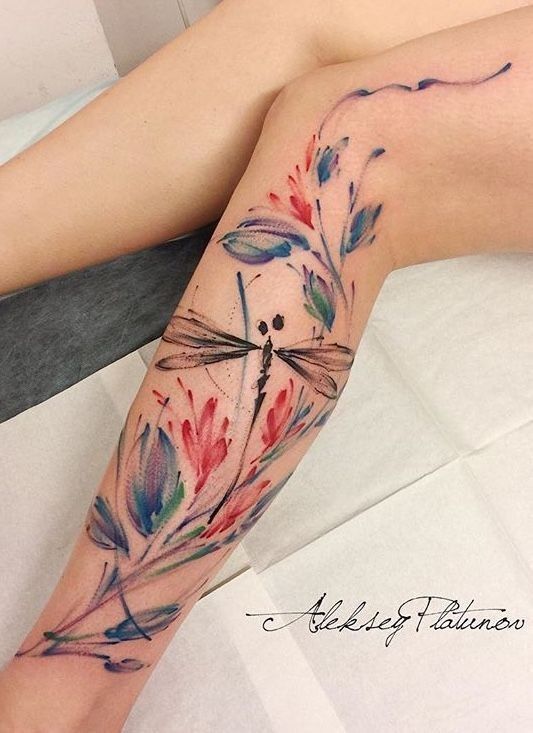 This may contain: a woman's leg with a dragonfly tattoo on it and watercolor flowers