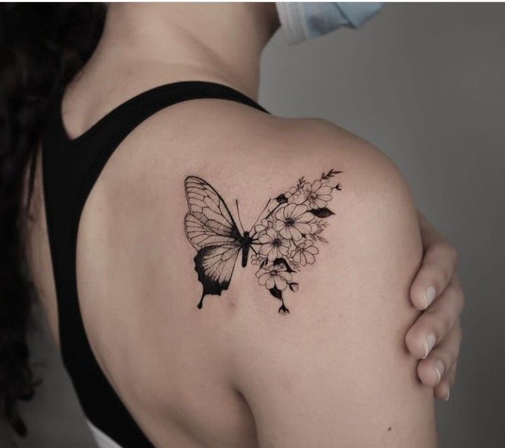 This may contain: a woman's back shoulder with a butterfly and flowers tattoo on her left arm