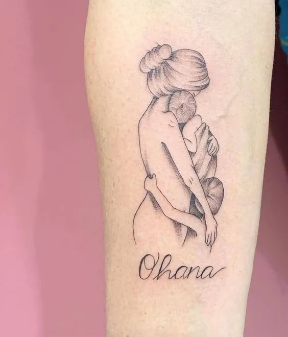 Tattoo of mother holding two children in her arms, showing sacred maternal love and protection.
