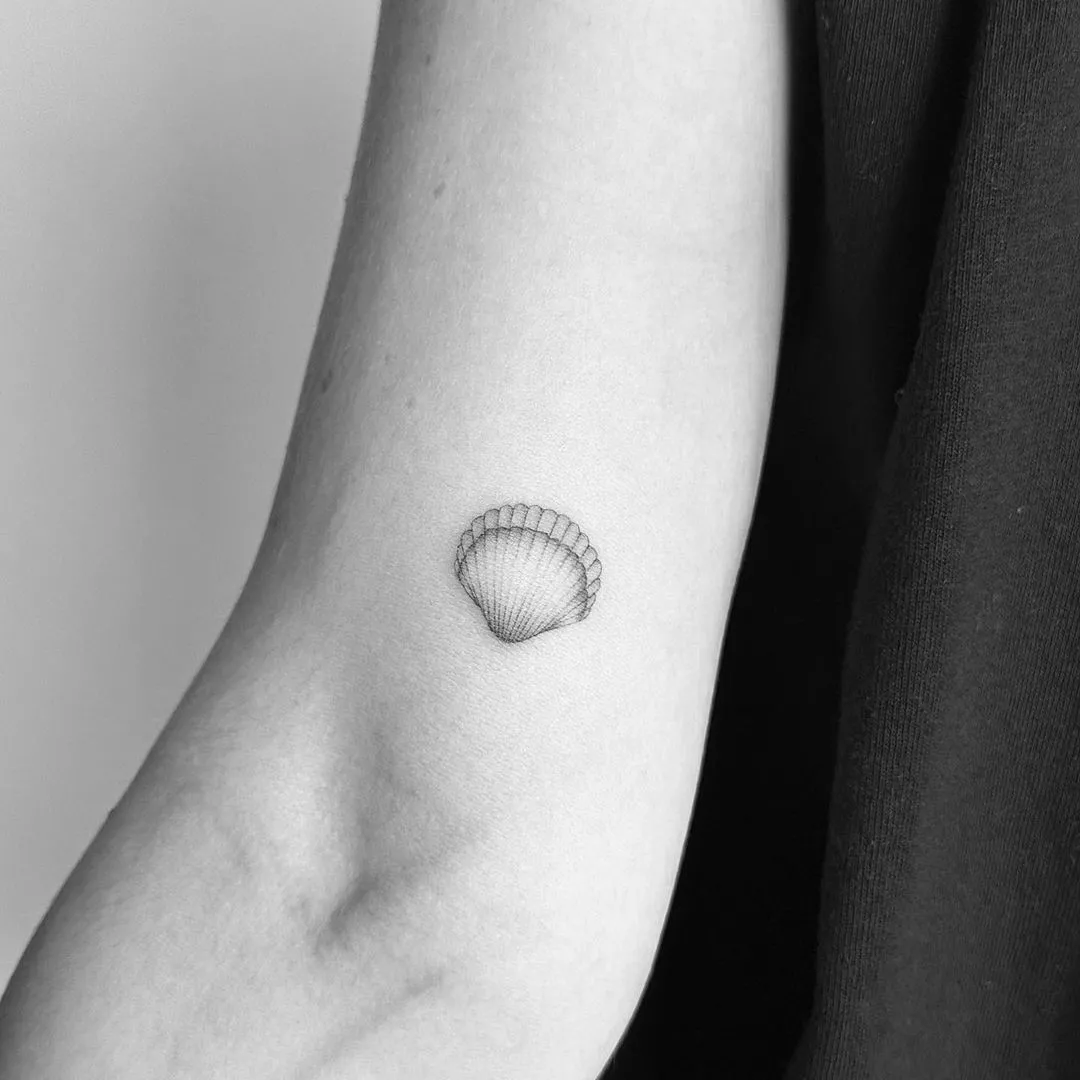 Person shows off the tiny tattoo of a shell on the inside of their arm