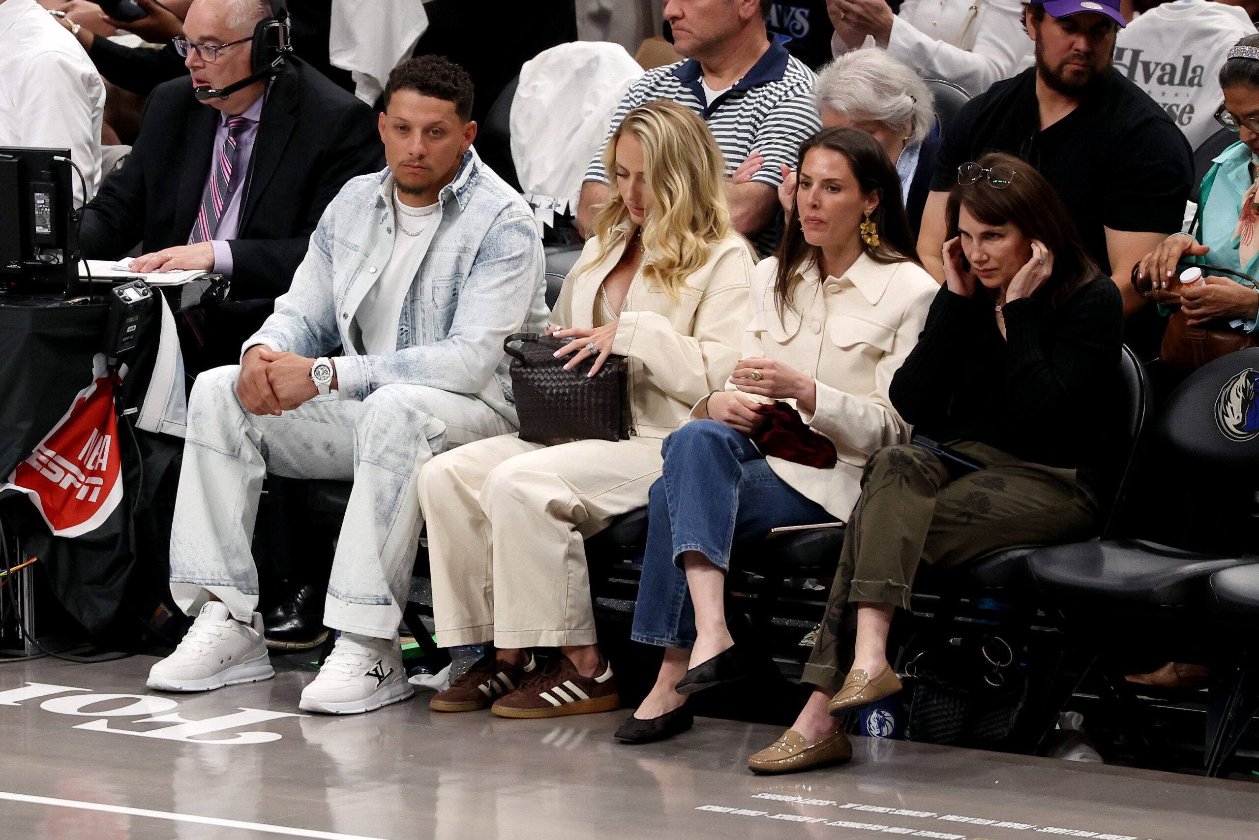 Patrick Mahomes and three women seated courtside at a basketball game.