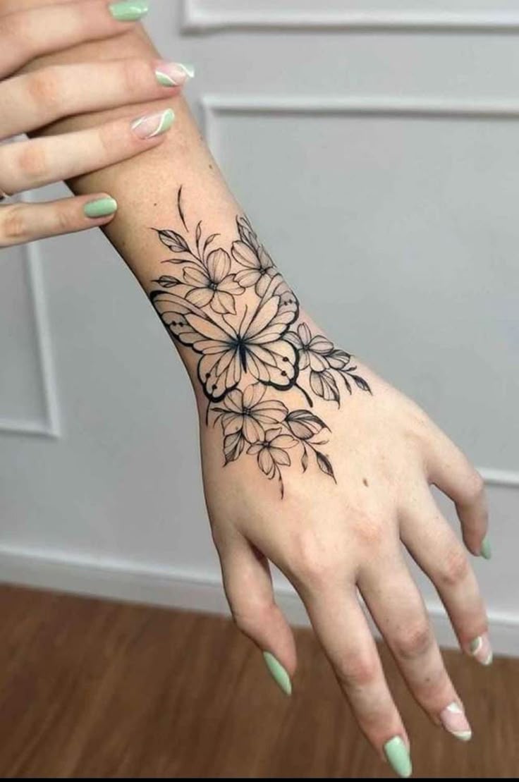 This may contain: a woman's hand with black and white flowers tattooed on the left side of her arm