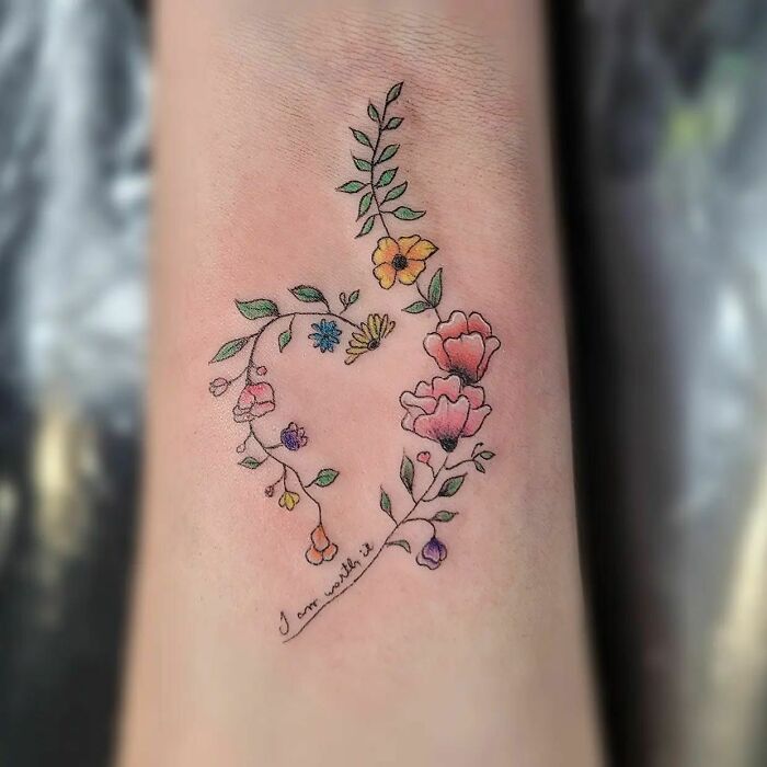 Delicate flower tattoo in a heart shape, featuring vibrant colors and leafy branches, radiates elegance and beauty. Delicate flower tattoo in a heart shape, featuring vibrant colors and leafy branches, radiates elegance and beauty.