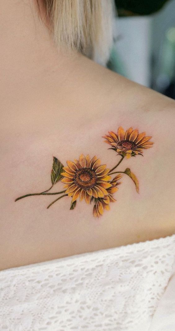This may contain: a sunflower tattoo on the back of a woman's shoulder, with two yellow flowers