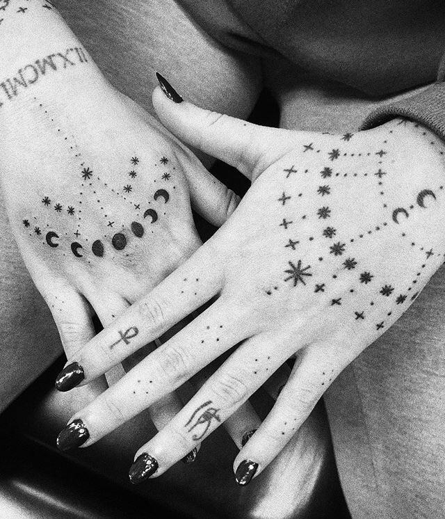 This may contain: a person with tattoos on their hands holding onto each other's palms and fingers